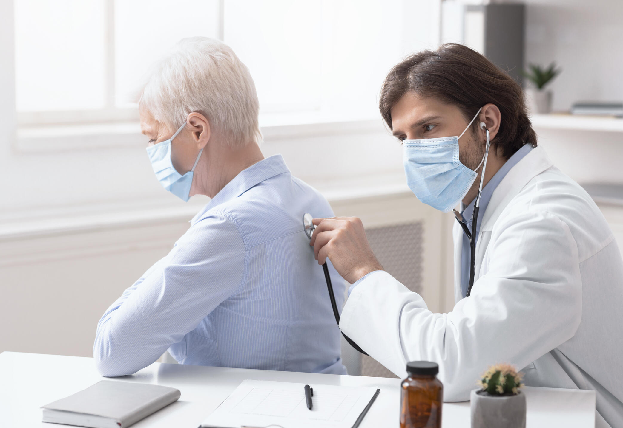 A primary care physician listens to a patient's breath. 
