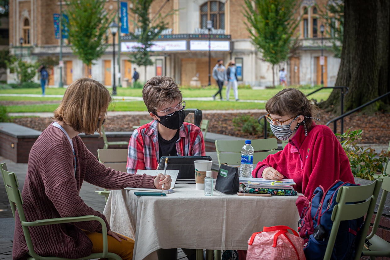 three VCU students wearing masks sit at a table in Monroe Park
