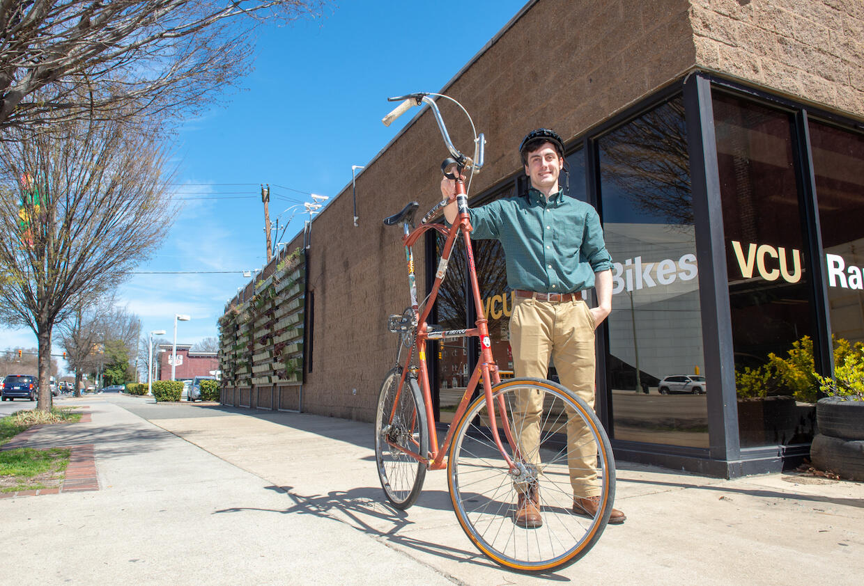 Man standing next to tall bike in front of RamBikes shop