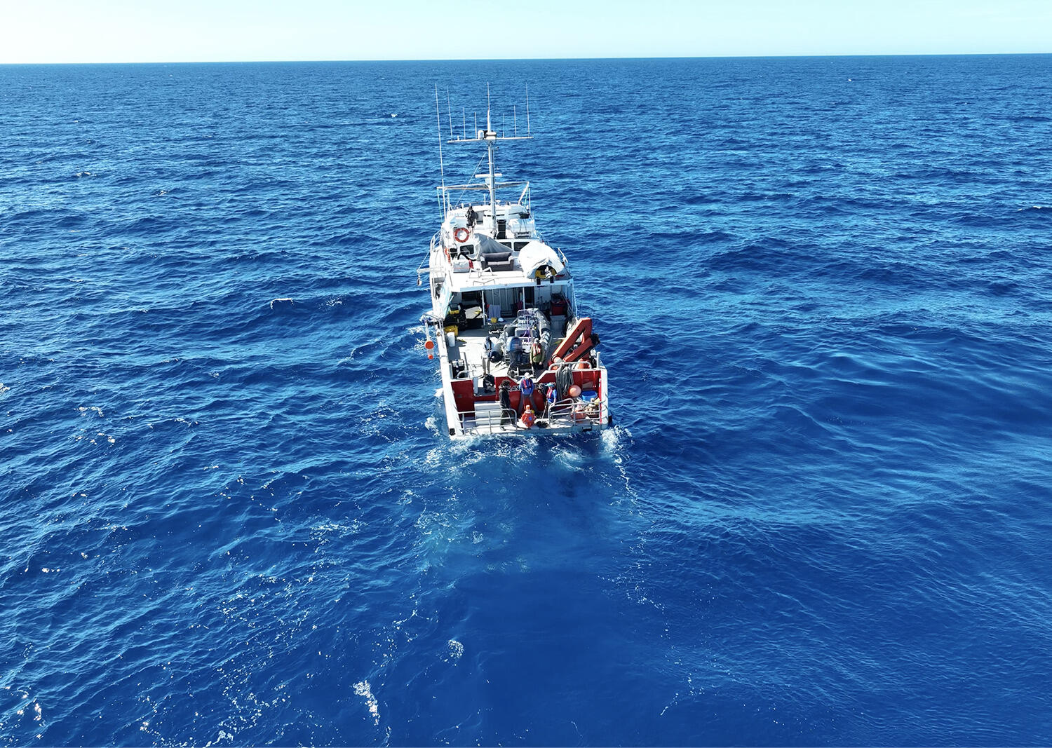 A photo of a boat traveling through bright blue ocean water. 
