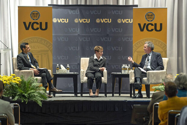 Three people sit in chairs under banners reading VCU.