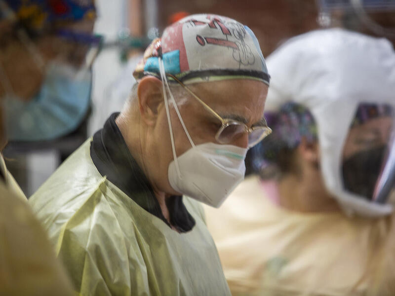 Three people in surgical masks and scrubs looking downward.