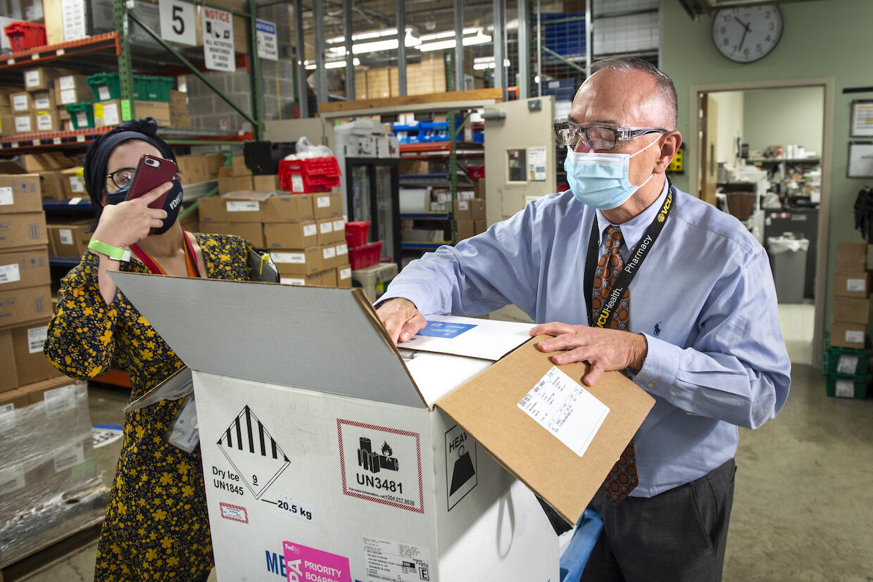 Rodney Stiltner and Sumayya Beekun opening a box of shipped COVID-19 vaccine.