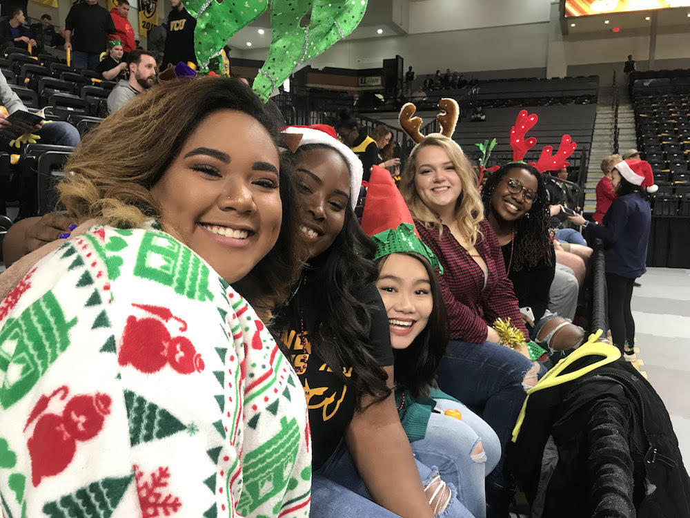Ieidi Cooper, left, takes a rare moment to sit with her friends and show off her holiday attire at a Christmastime game. Photo courtesy Ieidi Cooper.