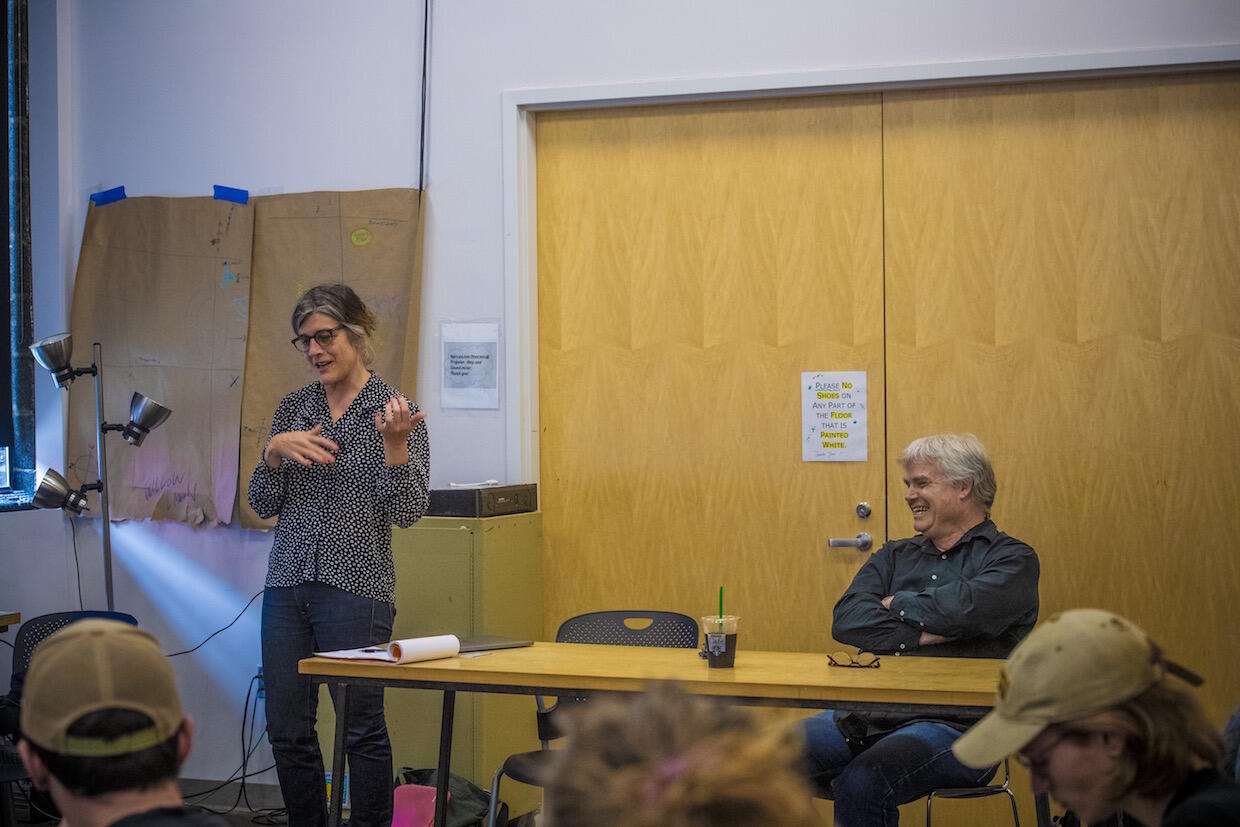 Rebecca Gates standing and lecturing during a VCU class with Brendan Canty, a musician.