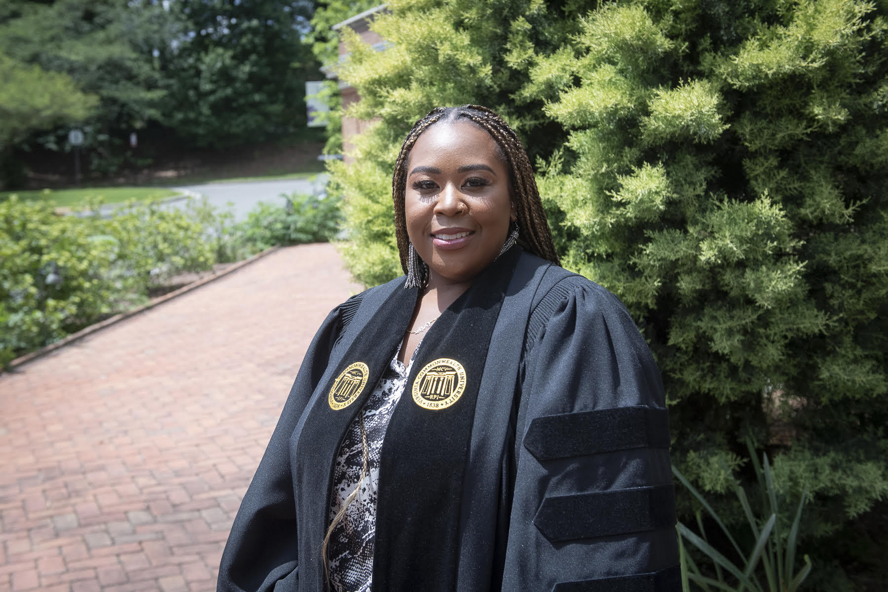 VCU graduate Briona Phillips, standing outside and wearing her graduation robe.