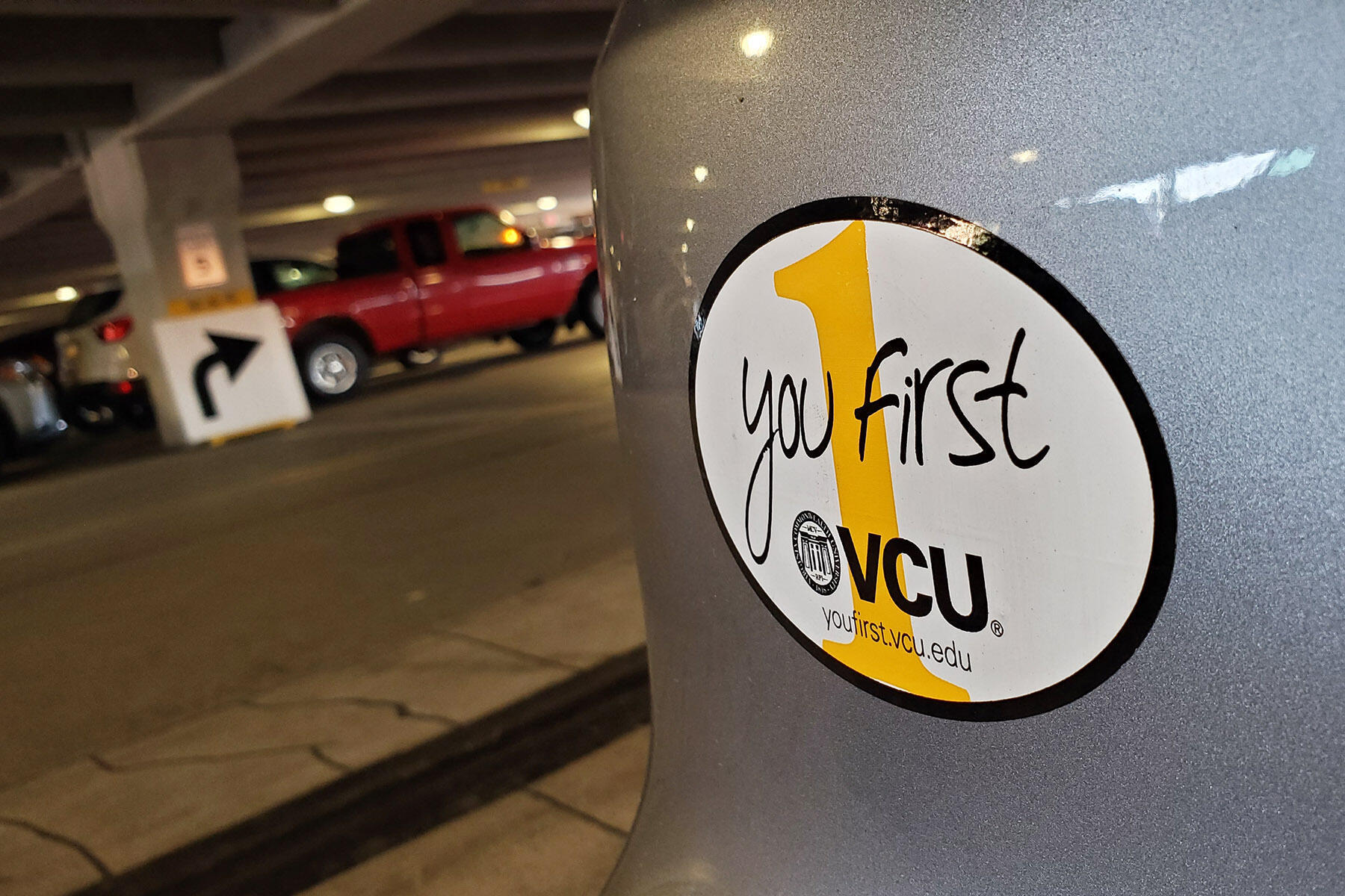 Bumper sticker on gray car that reads 'you first'. 