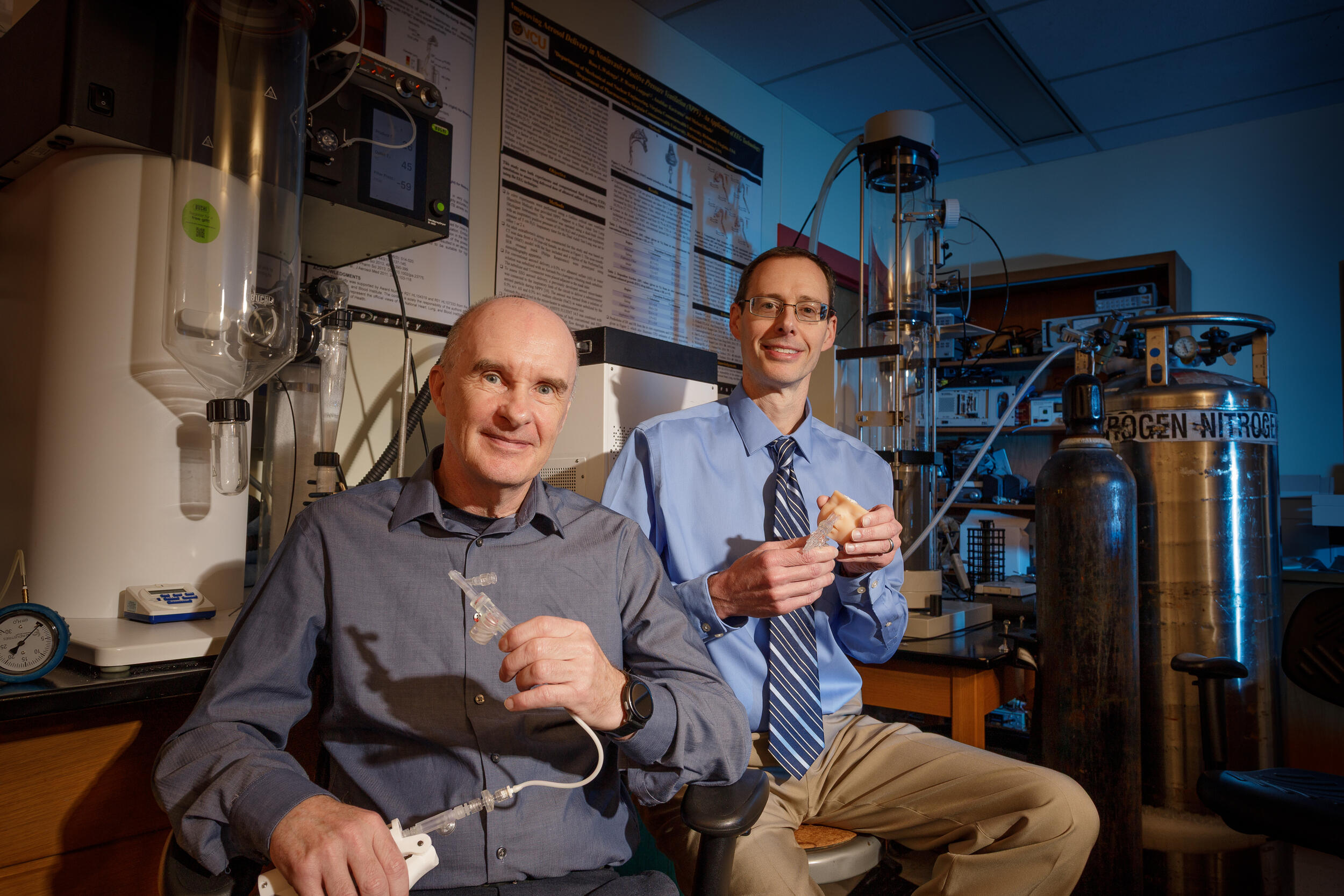 A photo of two men sitting in a research lab. 