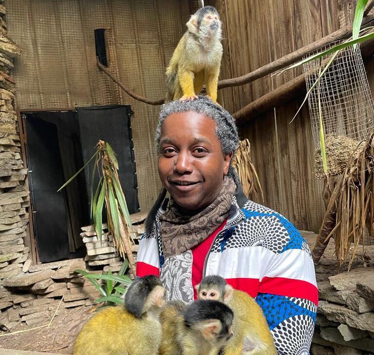 A photo of a person holding three monkeys while a fourth sits on top of their head