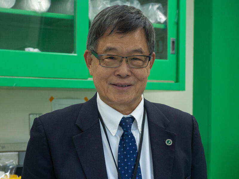 A photo of a man from the shoulders up wearing a suit, tie, button up shirt, and glasses. 