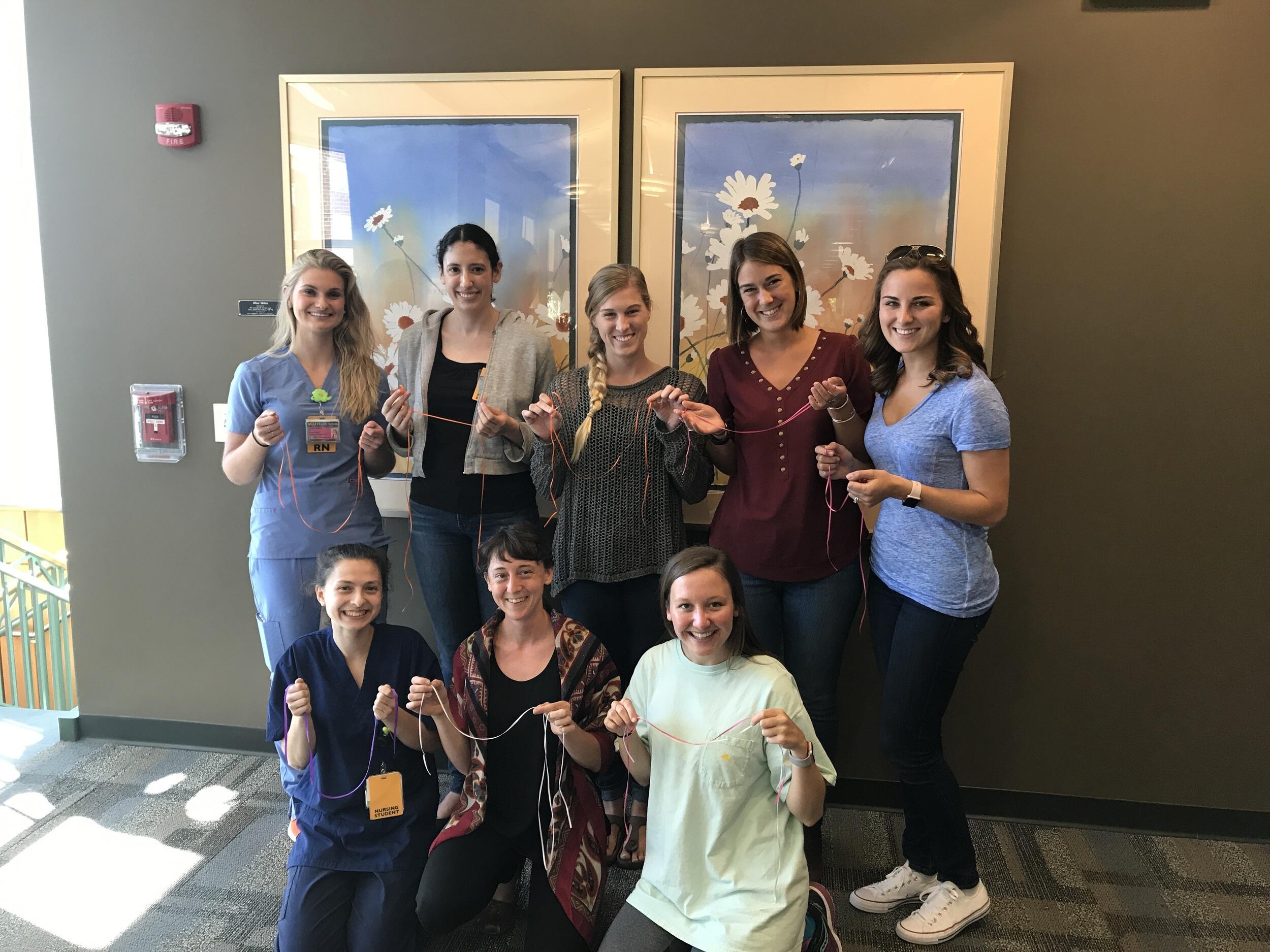 Participants in a recent doula training hold pieces of ribbon that symbolically bind the nursing students and trainers. The ribbons are tied together in a circle. After training, there is a ceremony where the ribbons are untied and placed in the birth bags of newly trained doulas.