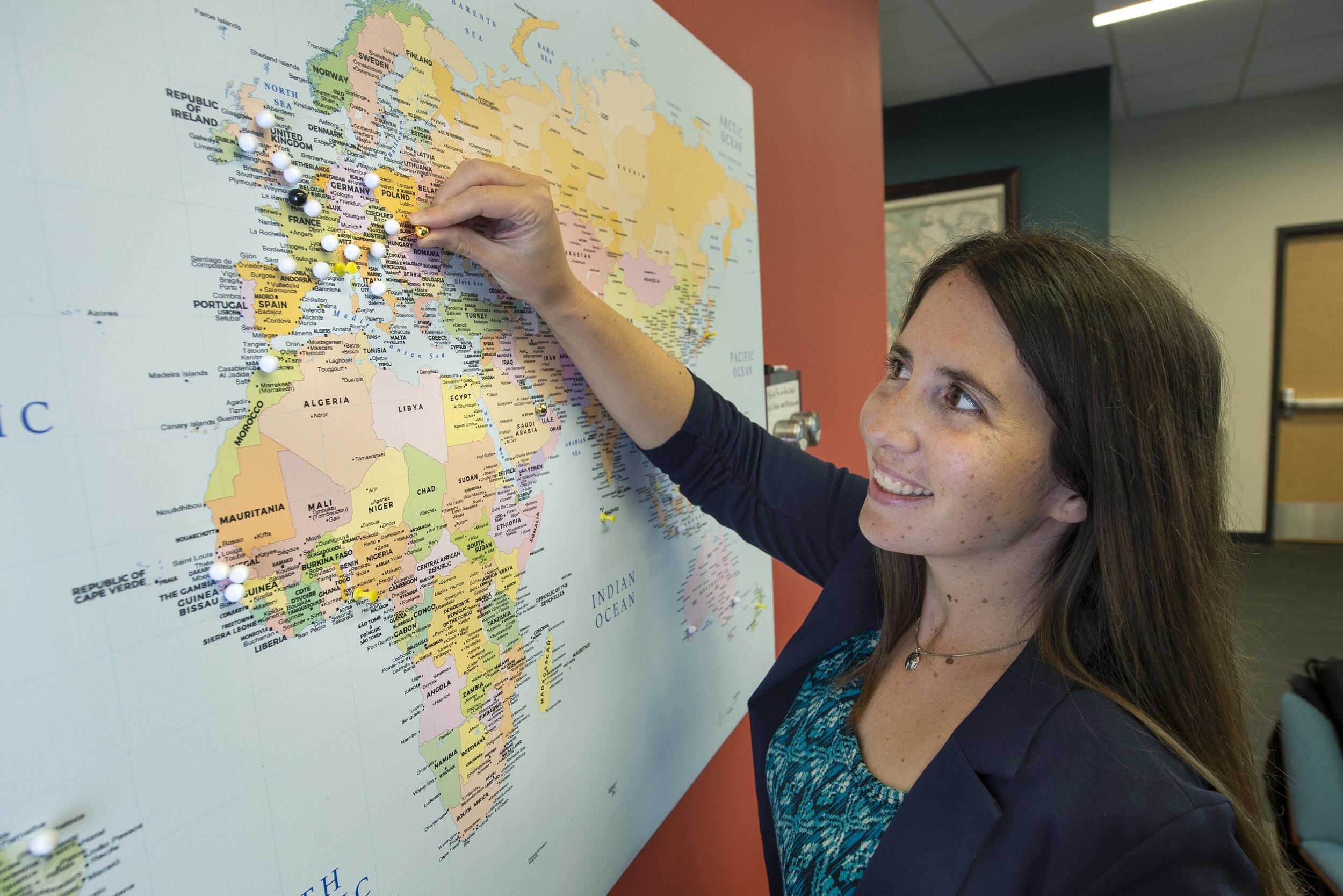 A photo of a woman putting a white pin on a map. 