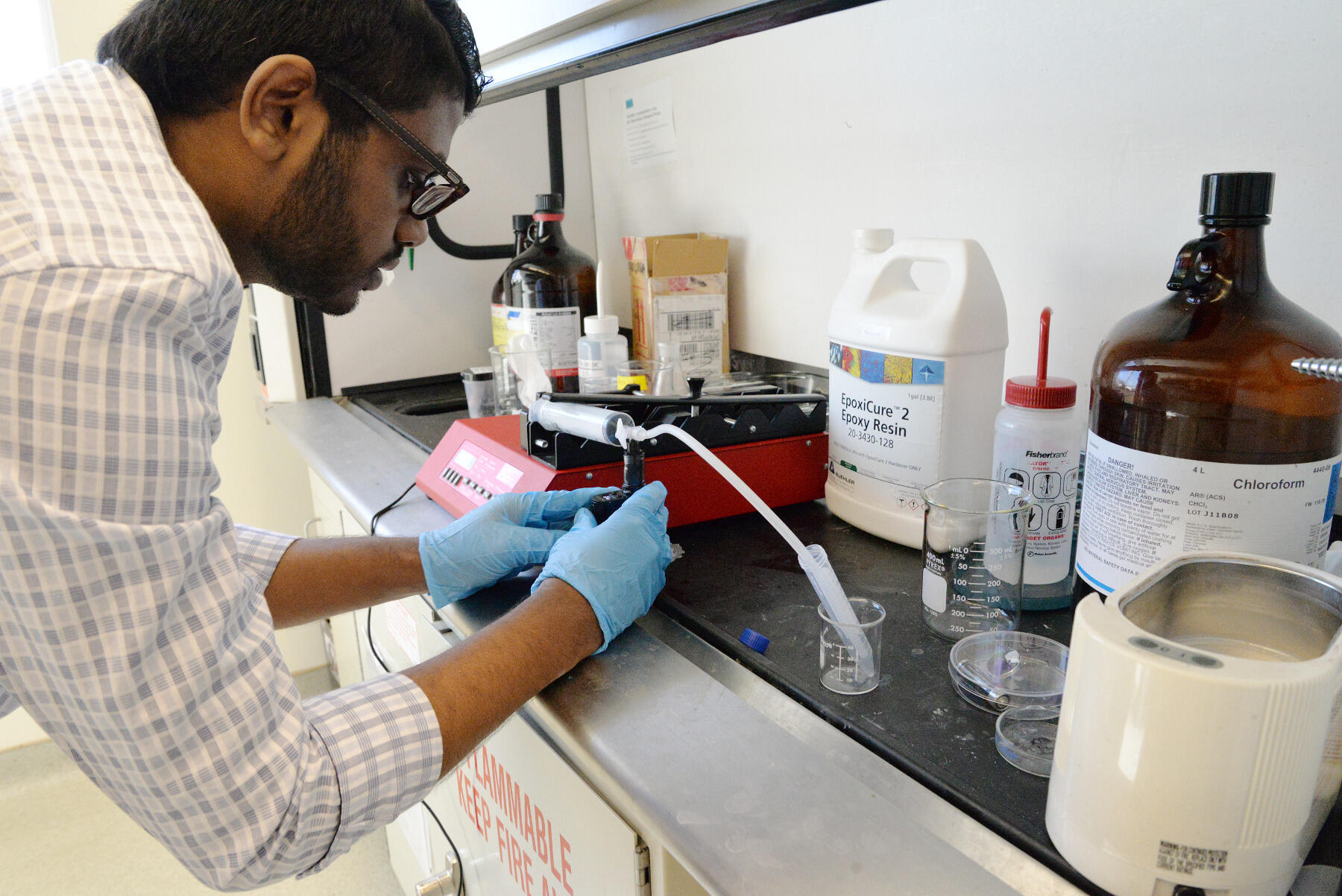 Suraj Kandalam, a biomedical engineering graduate student, works with a pump to infuse e-liquid vapor with saline to use during experimentation. The pump, which he created by modifying an apparatus that mimics smoking tobacco cigarettes, is meant to realistically simulate vaping. An atomizer heats up the e-liquid, turning it into vapor, which is then sucked through a syringe before it is infused with the saline. 
<br>Photo by Leah Small, University Public Affairs