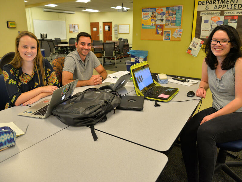 Three students sitting at a desk.
