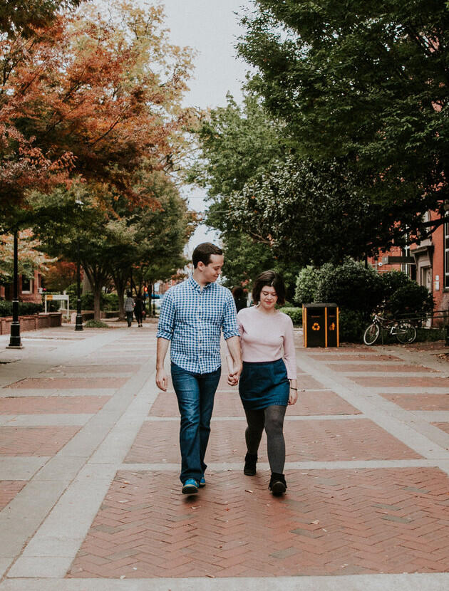 Two people walking on a brick path.