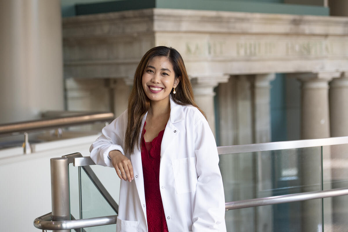 A photo of a woman smiling while wearing a white lab coat 