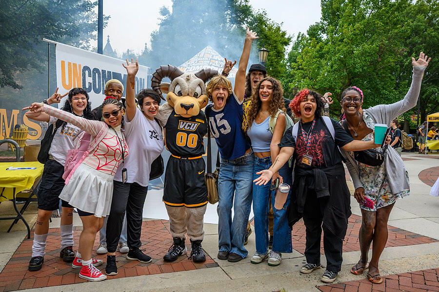 A group photo of nine people standing around Rodney the Ram. 