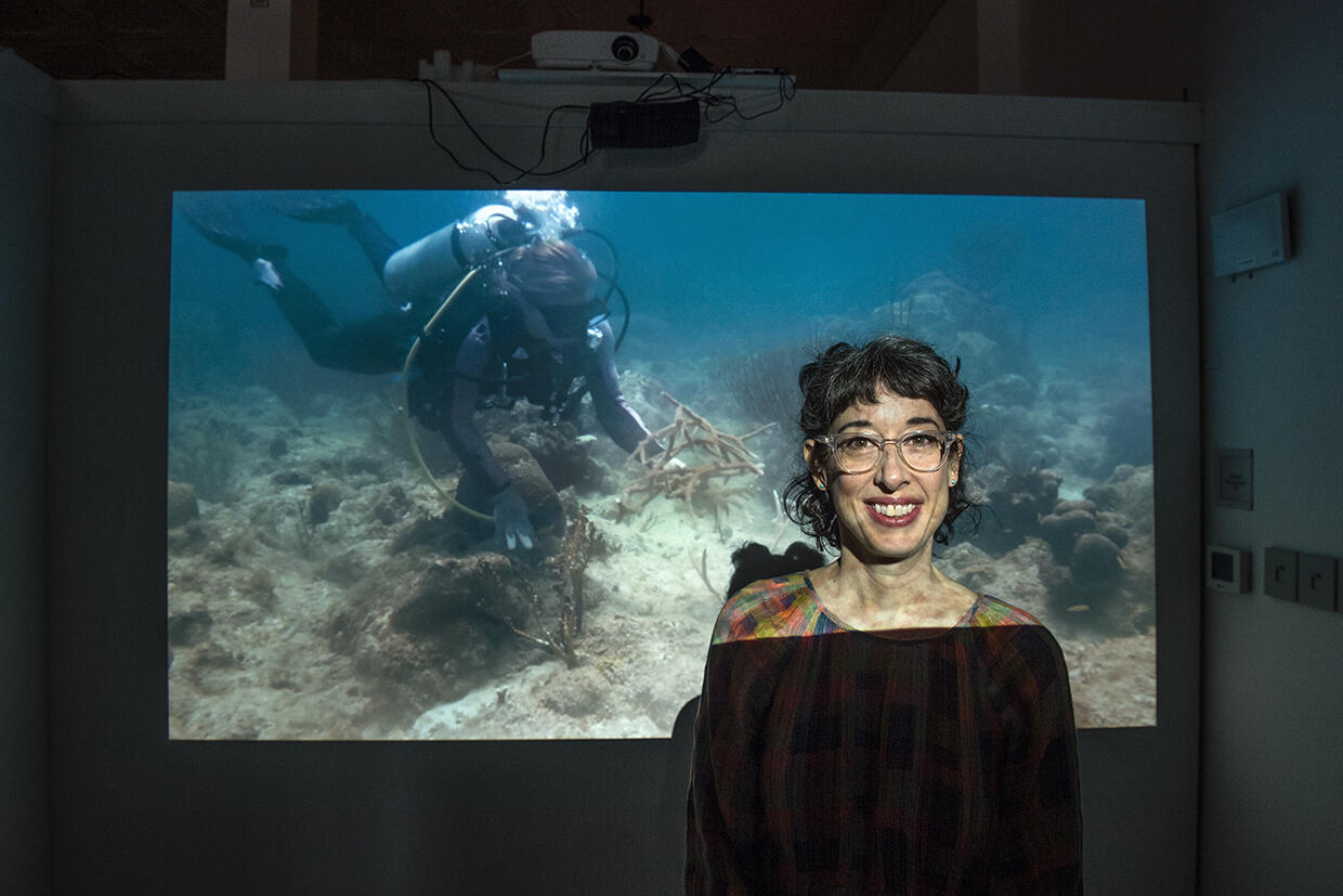 Woman standing in front of a projected image of an ocean scene.