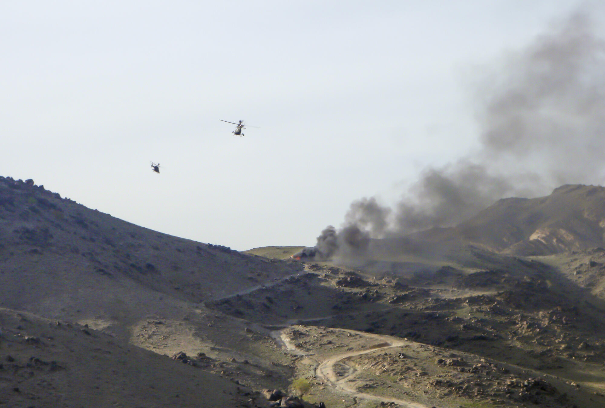 Helicopters flying over a bombing in Afghanistan.