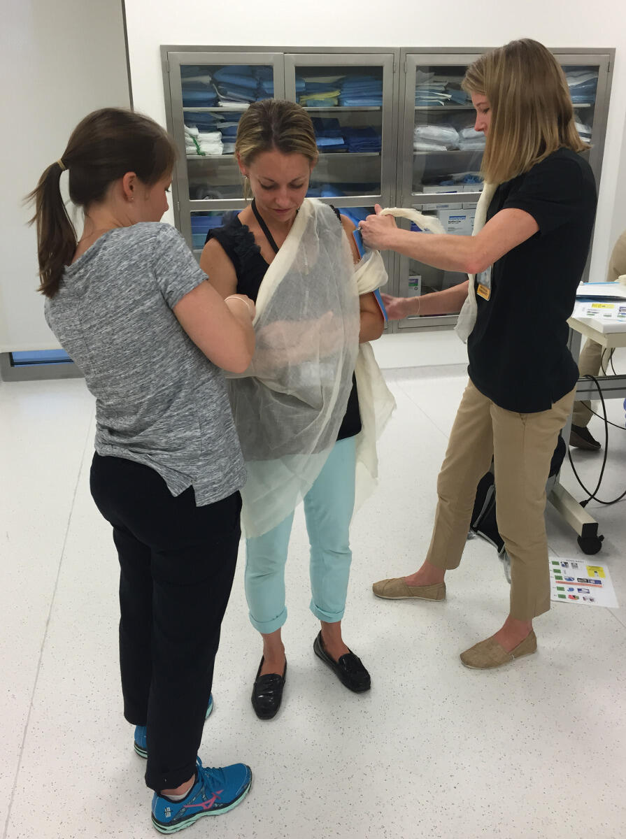 Jessica Dickerson, D.P.T., (left) and Ashley Harwood, D.P.T., (right) practice tying a sling around Rebecca Moran, D.P.T.