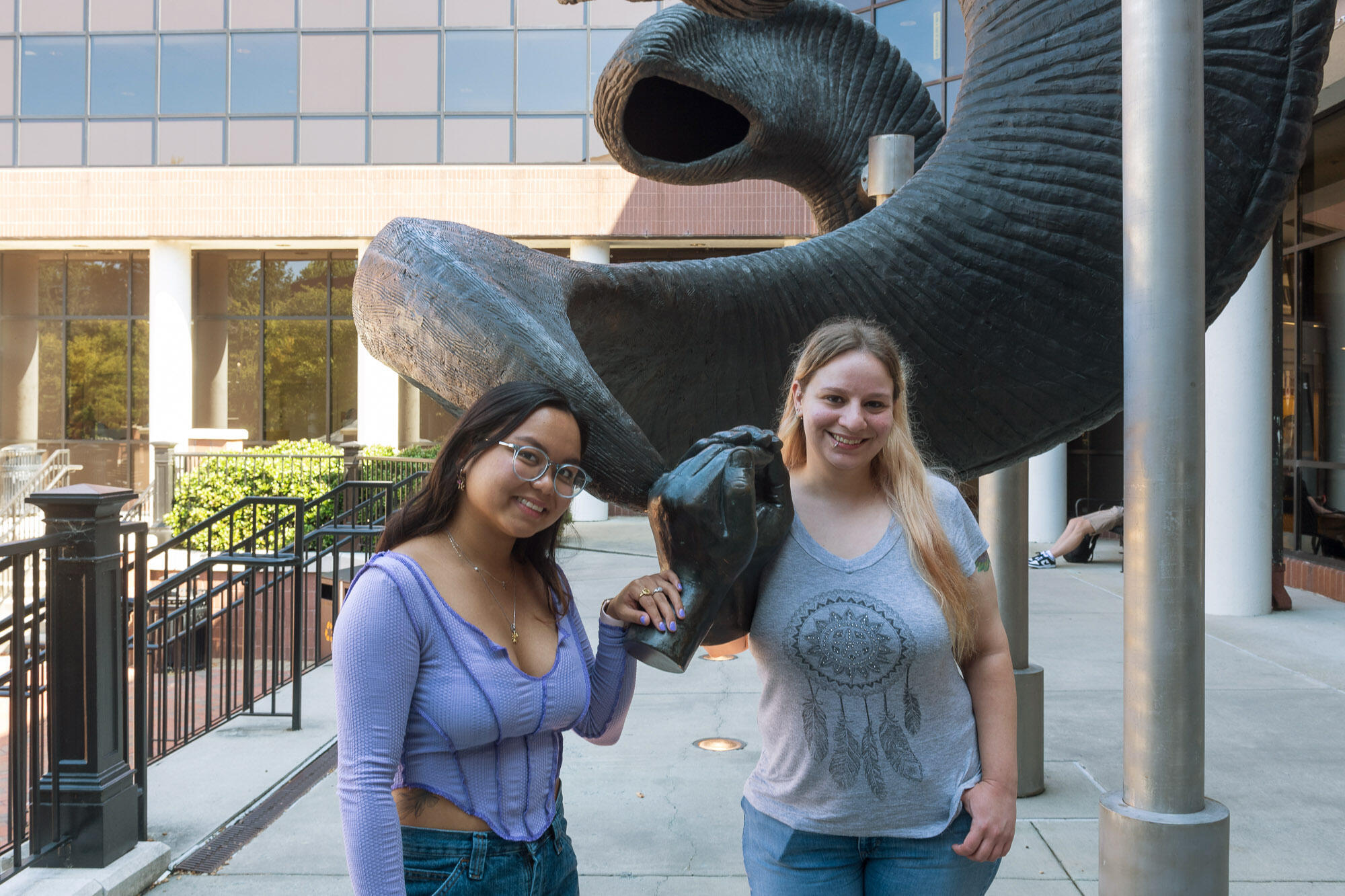 Two women standing in front of the ram horn statue at the Student Commons 
