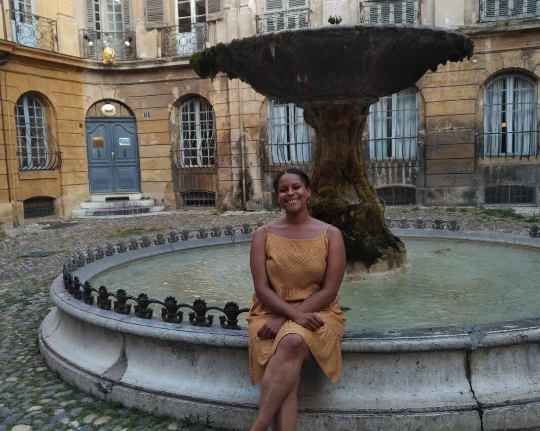 A woman sitting on the edge of a fountain. 