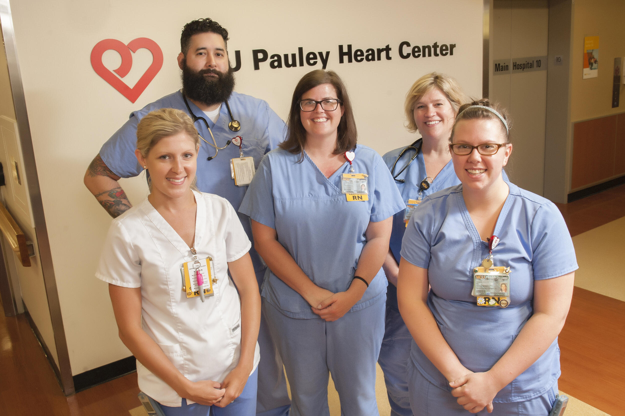 Five medical professional stands in front of a V C U Pauley Heart Center sign and logo on a wall.