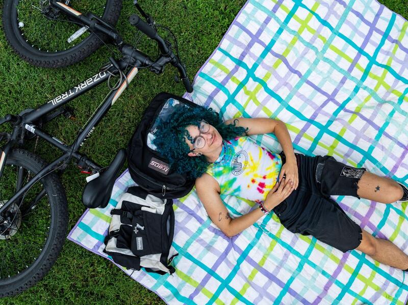 A view from above of a person lying on a blanket in the grass with a bicycle on the ground near their head.