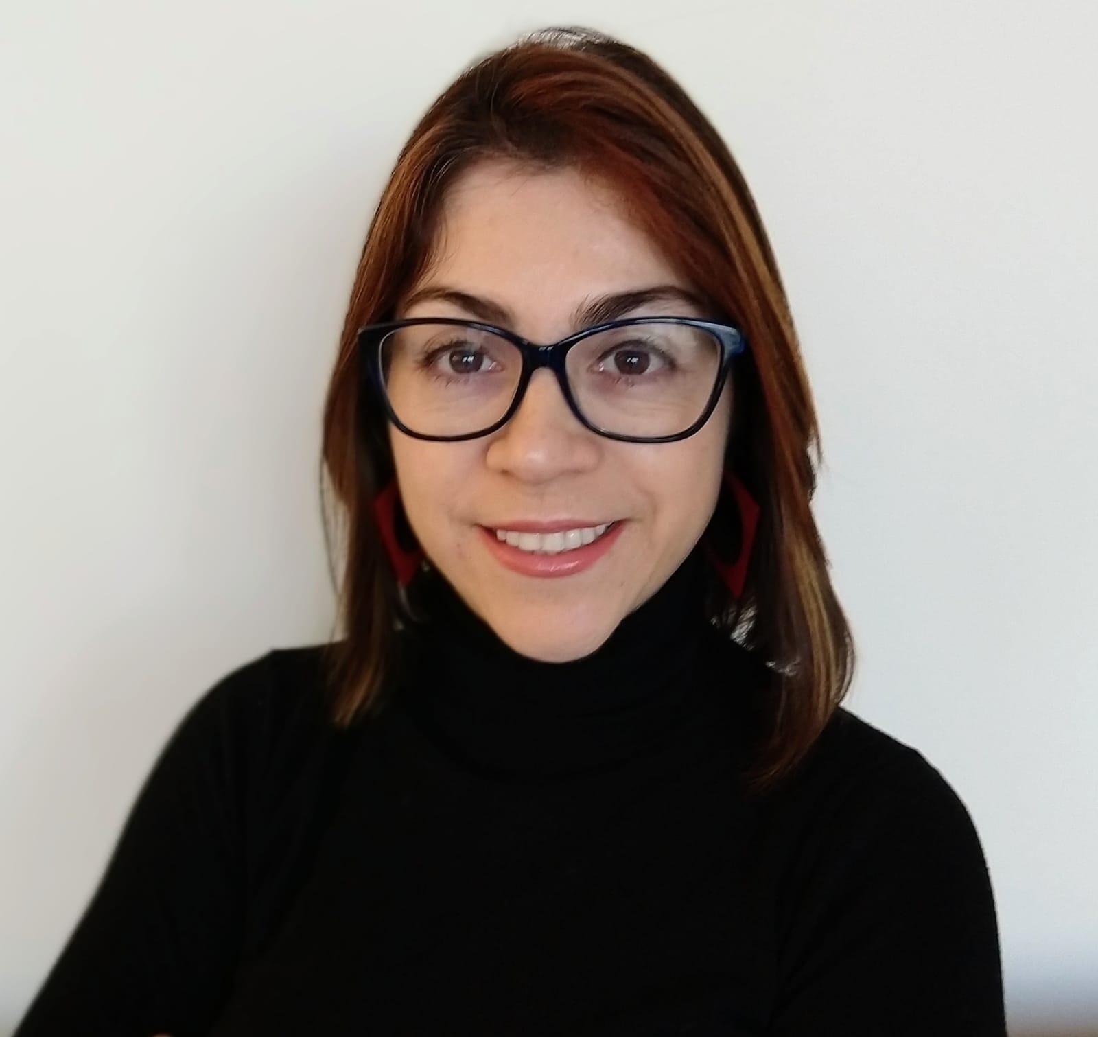 Head shot image of Paola Roldan, who is smiling and wearing glasses.