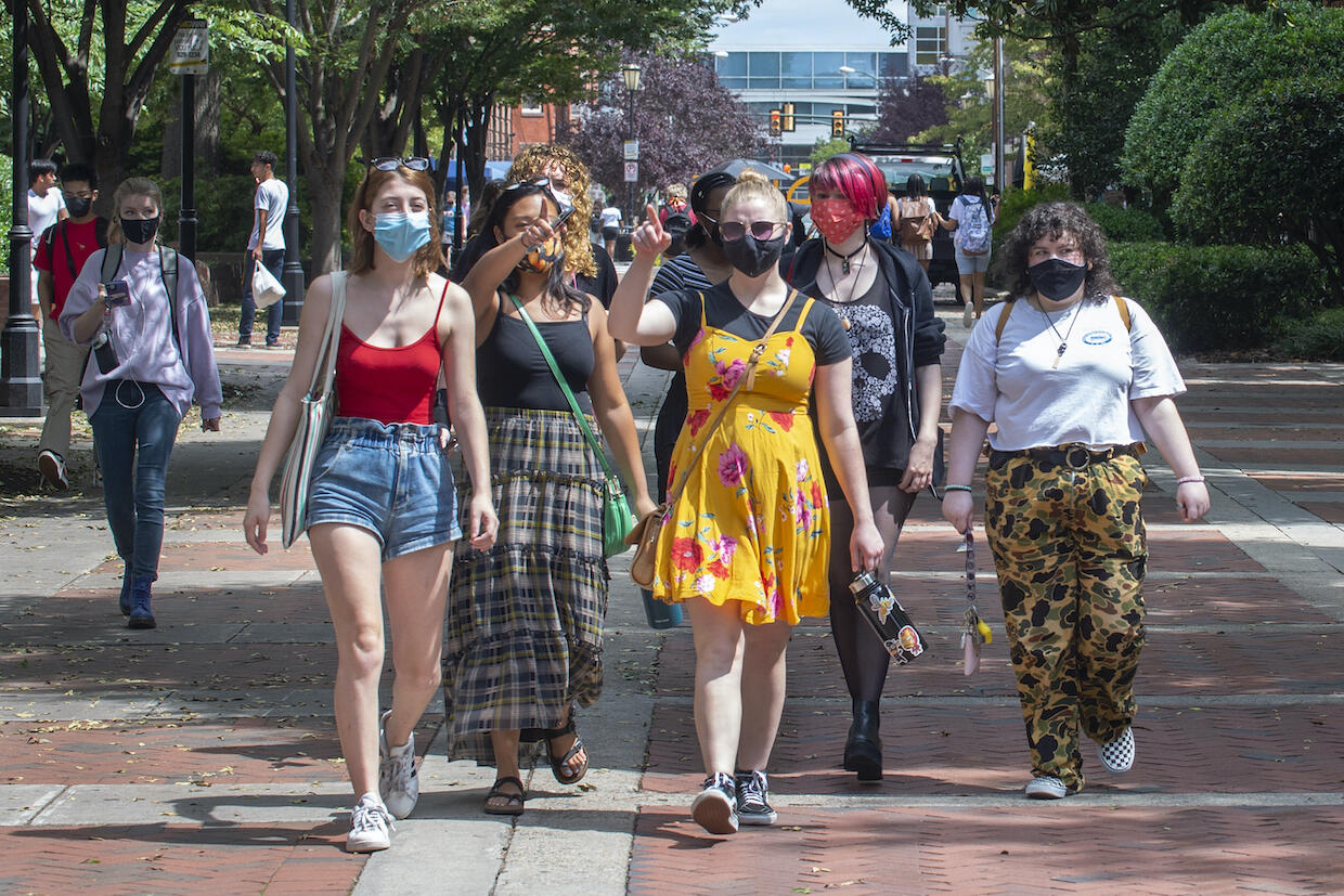 A group of students wearing masks walks toward The Compass on the first day of classes.