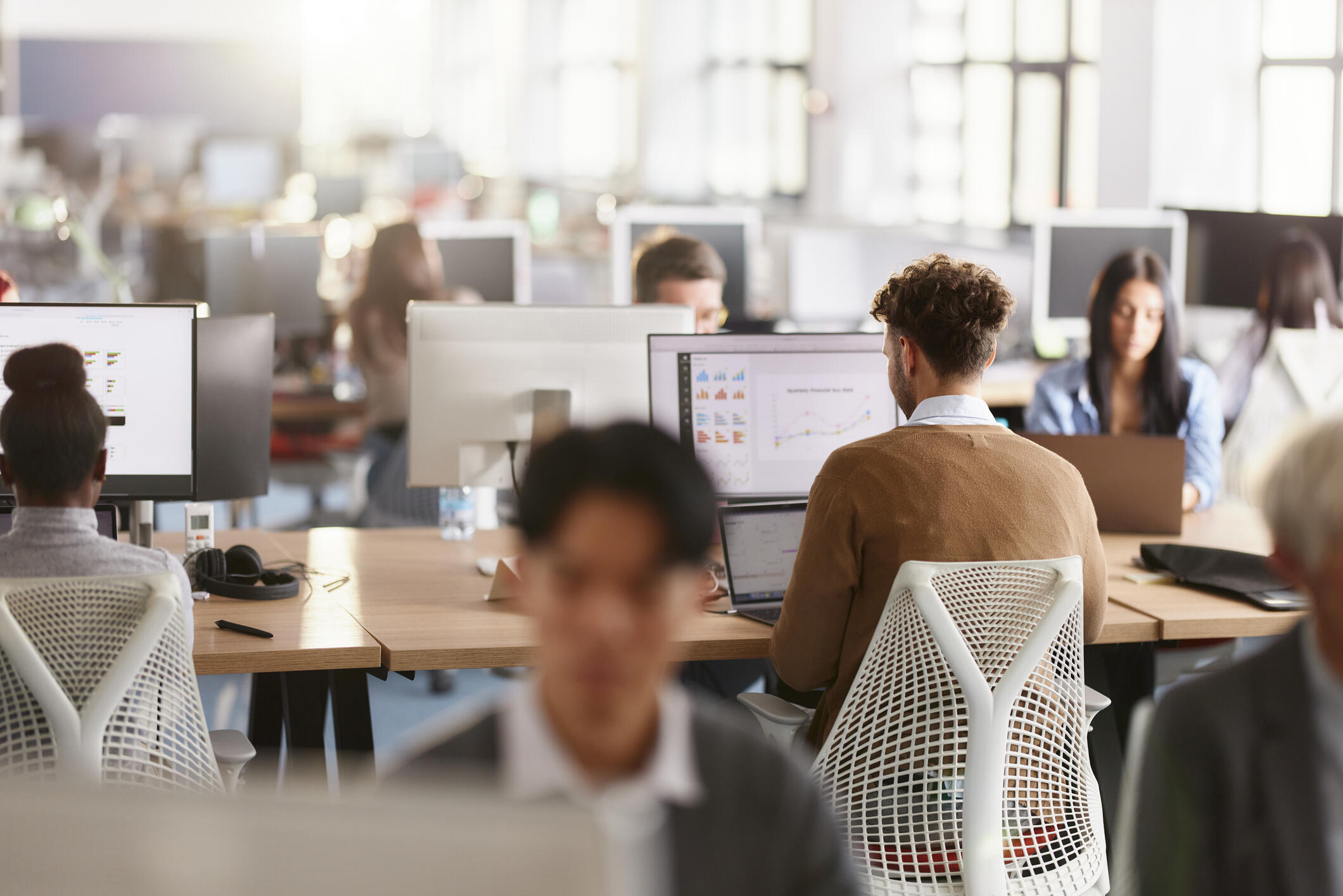 A photo of an office full of people sitting at desks with computers. 