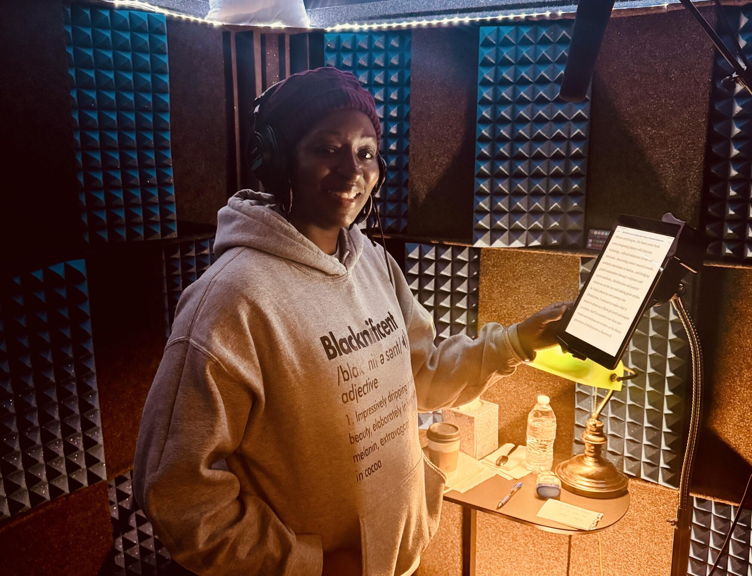 A woman in a hooded sweatshirt stands in front of a microphone.