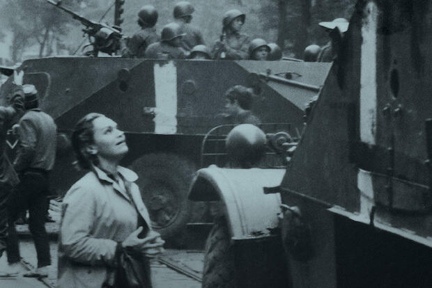 A woman looks up at an armored vehicle.