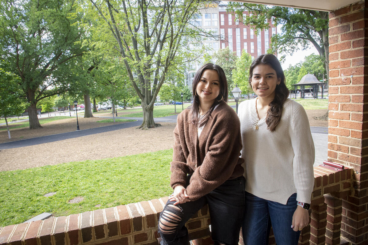 Daniela Negrete and Mariana Fernandes Gragnani in front of a short brick wall with Monroe Park in the background.