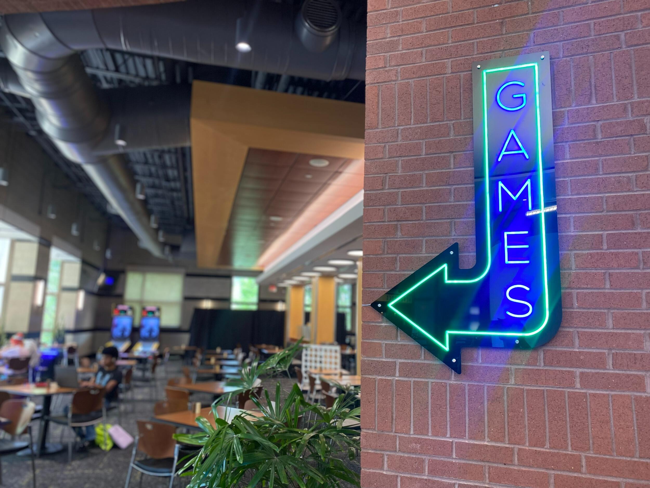 A photo of a neon sign that says \"GAMES\" hung on a brick wall 