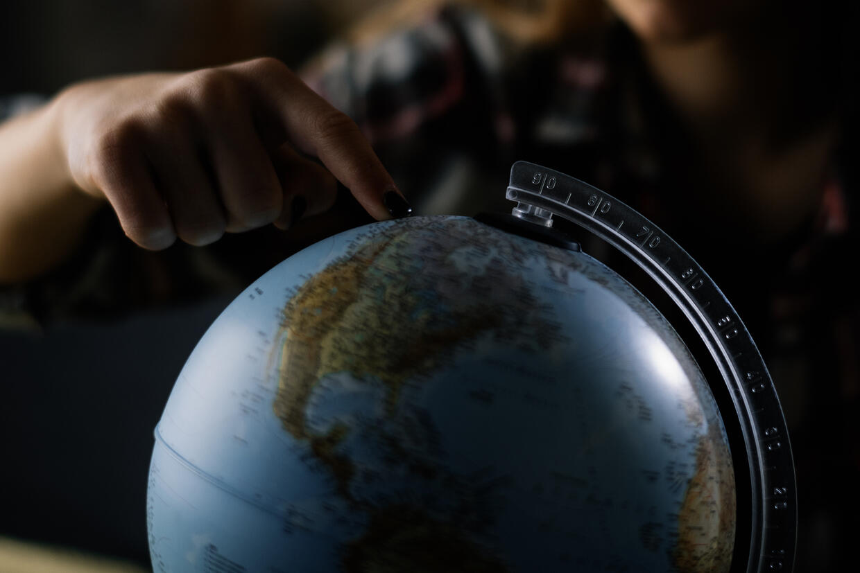 A person points to a globe map.