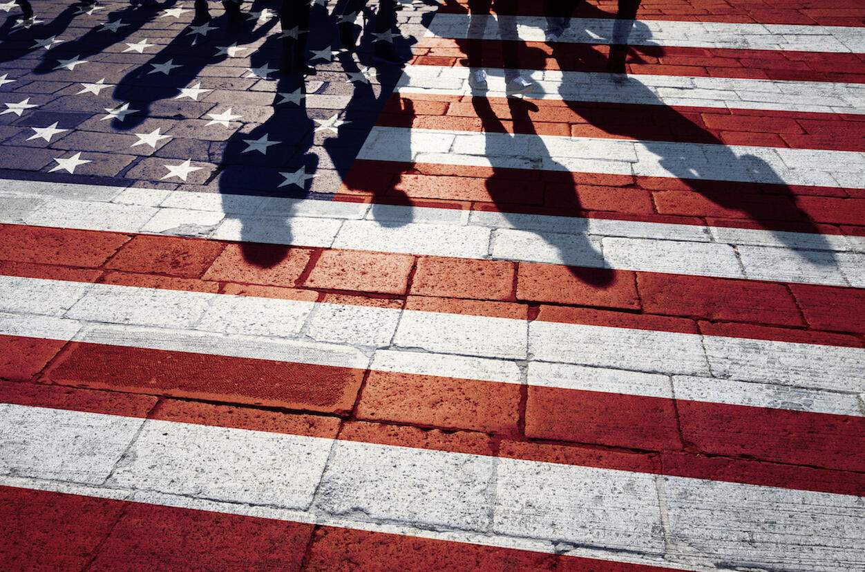 Shadows of people are reflected on a painted version of the United States flag.