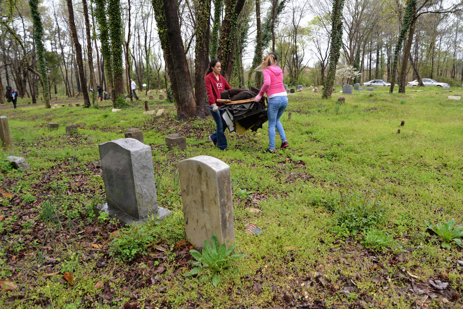Alexis Meijias, a junior sociology major, and Victoria Mills, a senior science major, carry out trash from East End Cemetery.