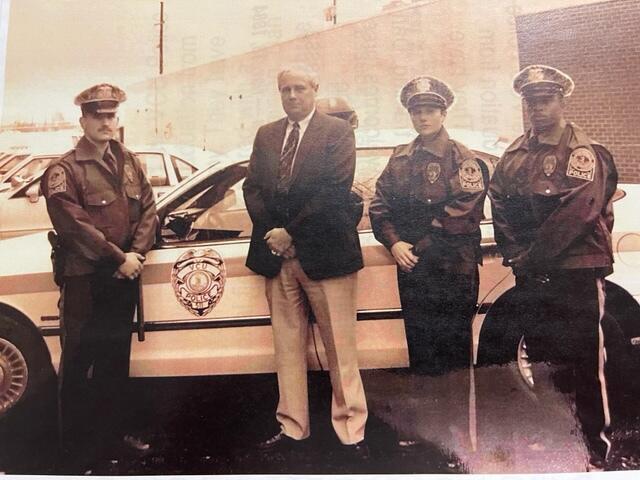 A black and white photo of VCU Police Chief Dan Dean and three police officers standing in front of a police car in 1994. 