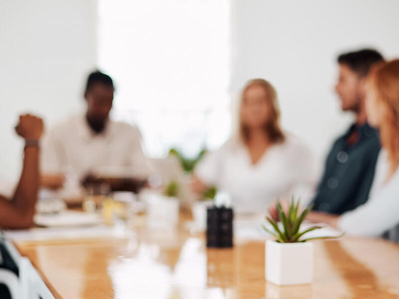 A blurry photo of five people sitting around a conference table. 