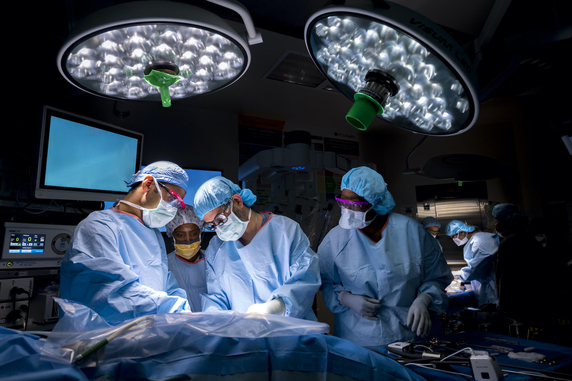 Four people in scrubs perform surgery.