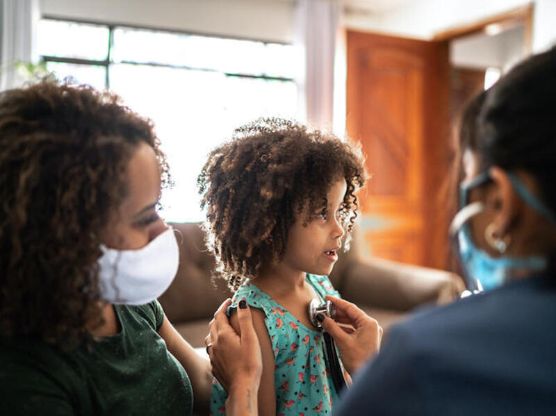 A doctor gives a child a checkup with a parent next to them.