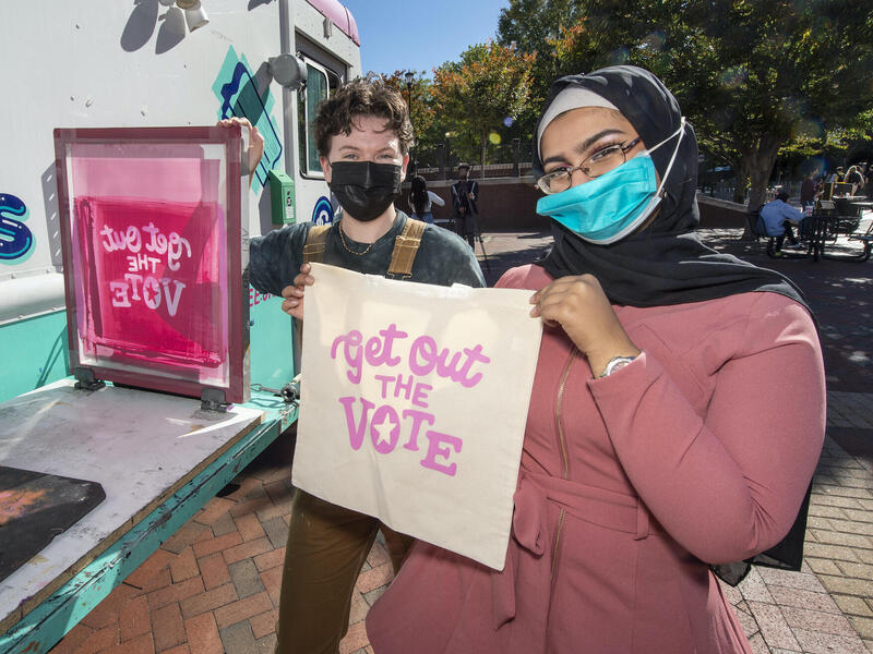 Holding up screen-printed tote bags at a VCU Votes event on Oct. 27. (Kevin Morley, University Marketing)
