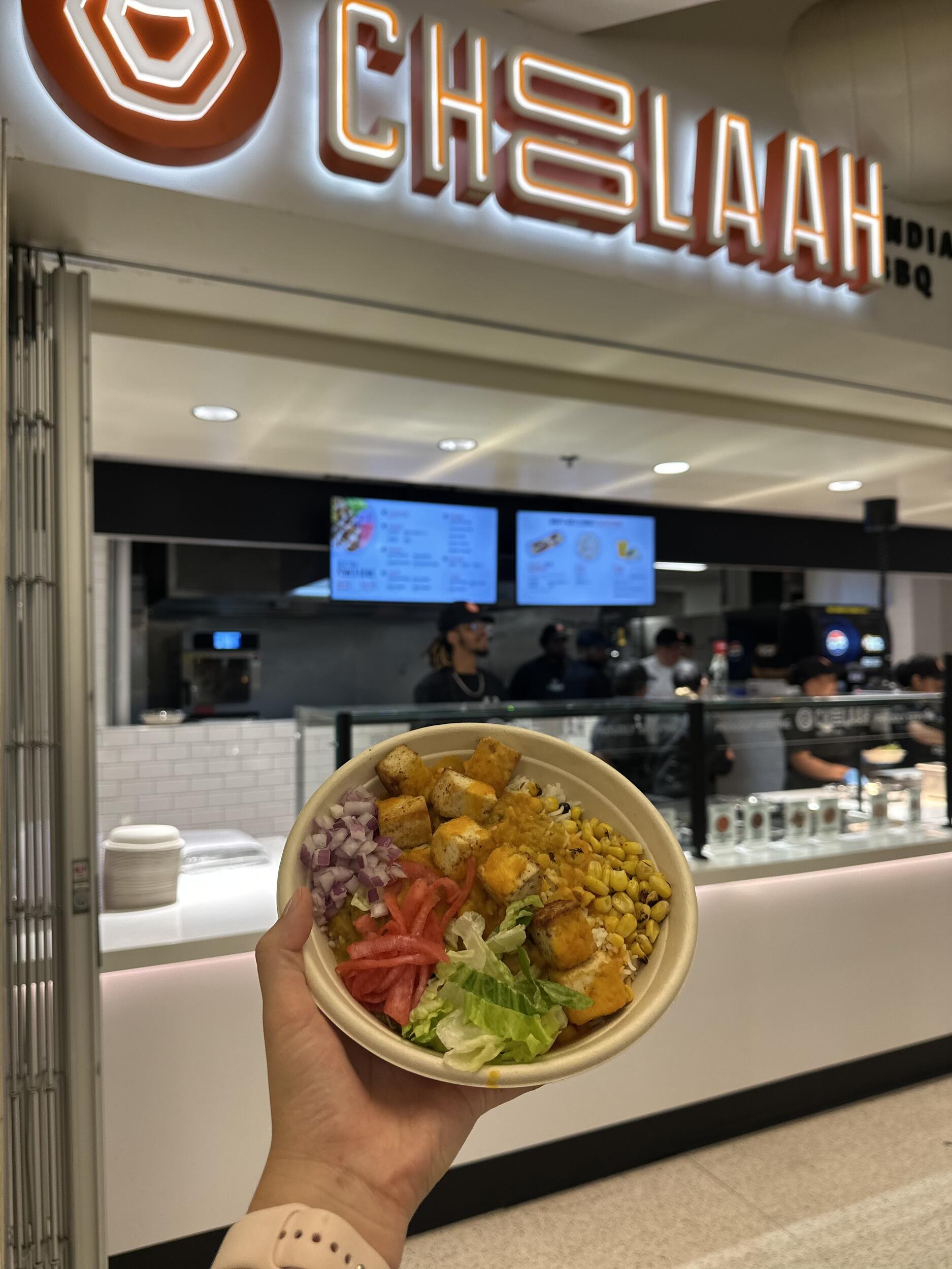 A photo of a bowl off food in front of a sign that says \"Choolaah\"