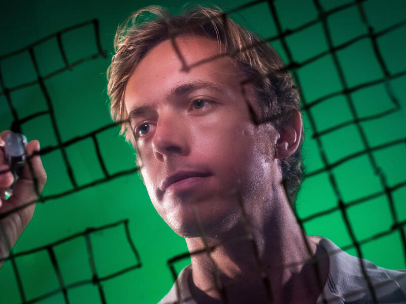 A photo of a man holding a marker. Around him are crossword squares. 