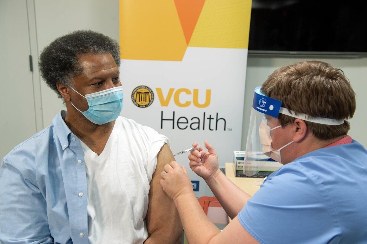Robert Winn, left, receiving a COVID-19 vaccination shot from a VCU Health colleague.