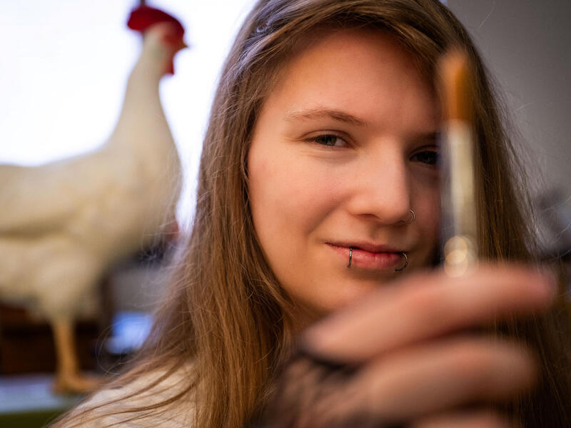 A woman holds a pen or marker up in front of her.