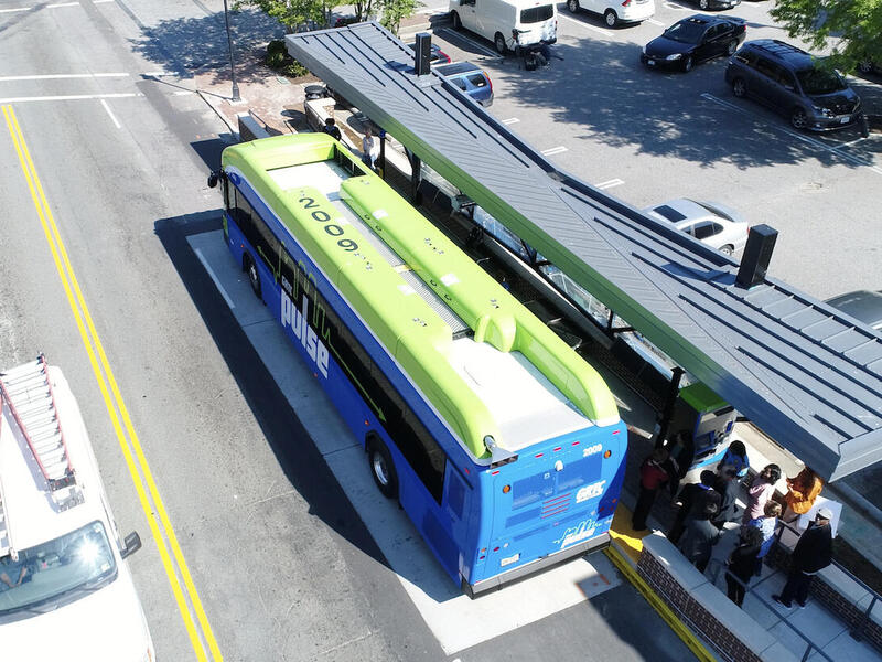 Overhead shot of a blue and green bus at a station.