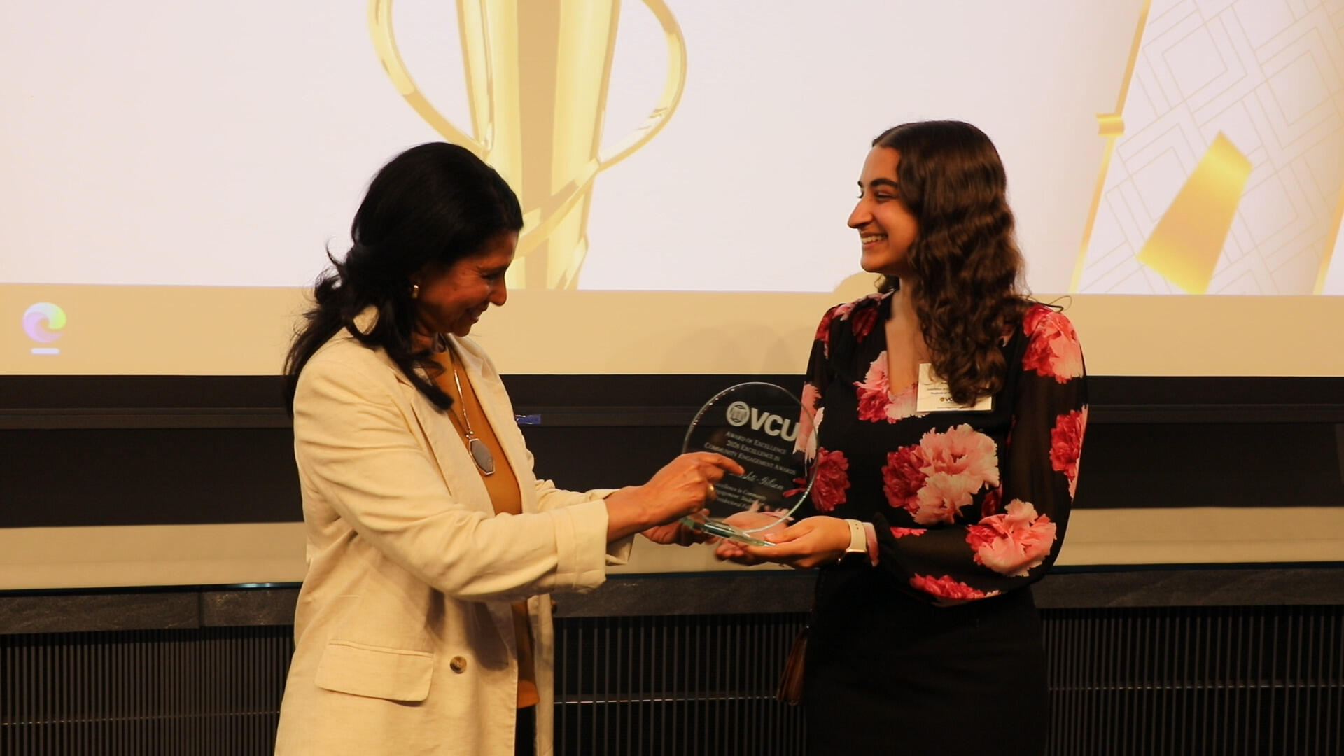 A woman hands an award to another woman.