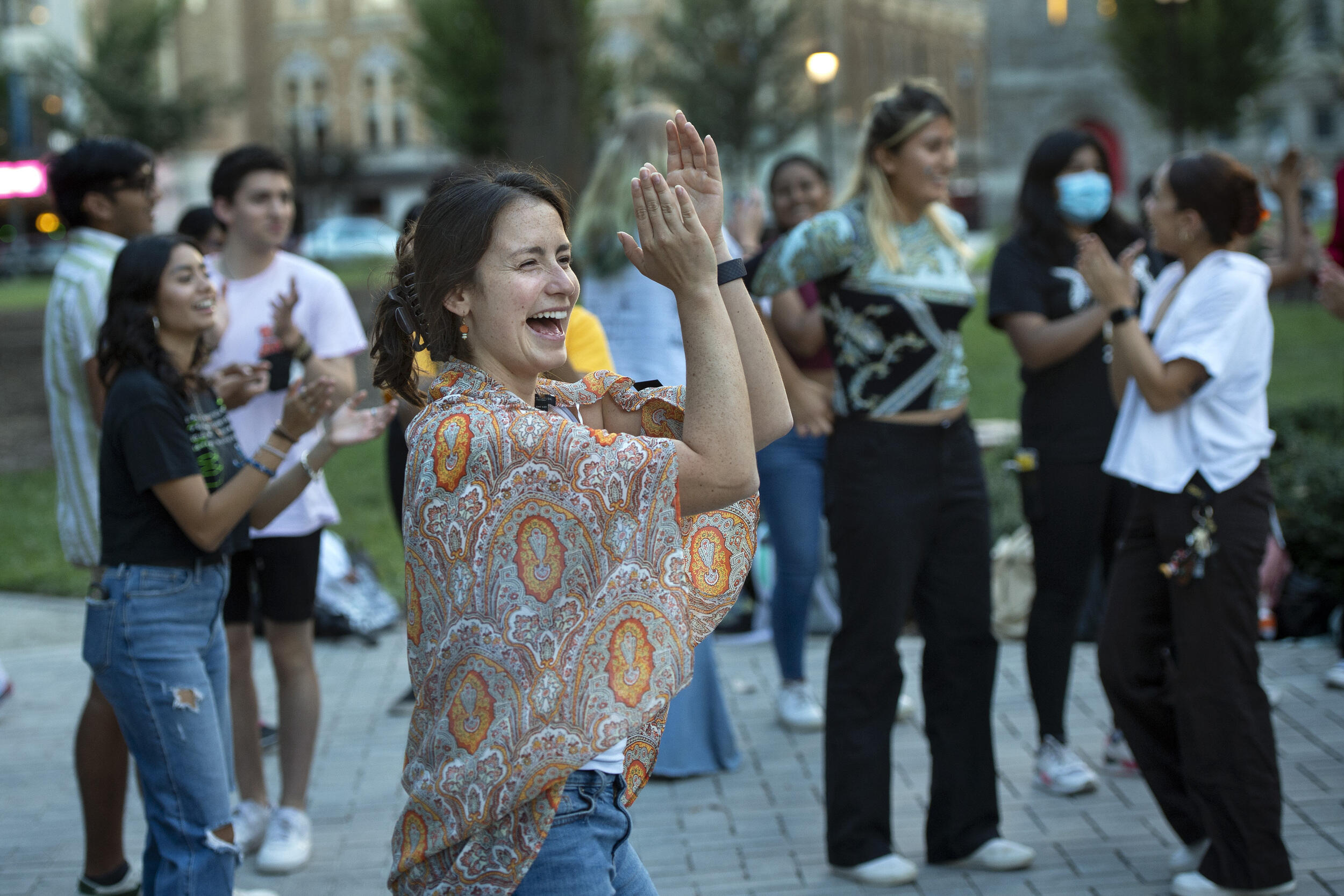 A woman clapping her hands in front of a group of people 